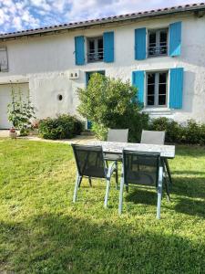 ein Tisch und Stühle vor einem Haus in der Unterkunft Maison charmante à Antezant-la-Chapelle avec jardin in Le Pin-Saint-Denis