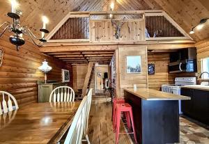 a kitchen with wooden walls and a counter with a red stool at Le Refuge au Mont Comi in Saint-Gabriel