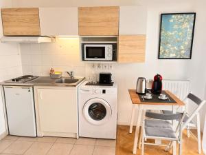 a kitchen with a washing machine and a table at Studio à 3 min Gare Massy-TGV in Massy
