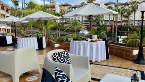 a restaurant with tables and umbrellas in a courtyard at Hotel Puerto Palace in Puerto de la Cruz
