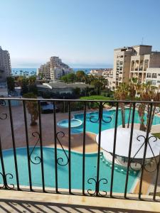 une vue sur une piscine depuis un balcon dans l'établissement Apartamento reformado con terraza vistas al mar y a las piscinas de Magic World garaje y piscina frente a Balneario Aire acondicionadowifi, à Oropesa del Mar