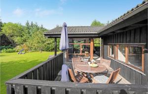 a deck with a table and chairs and an umbrella at Holiday Home Rønnevej Fjerritslev Ix in Fjerritslev