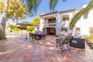 Charming Villa in Teulada with Private Pool في تيولادا: فناء به طاولات وكراسي أمام المنزل