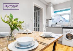 a kitchen with a wooden table with bowls on it at Cosy 3-Bedroom Serviced House with Free Fast WiFi and Parking for 2 Cars By Redwood Stays in Camberley