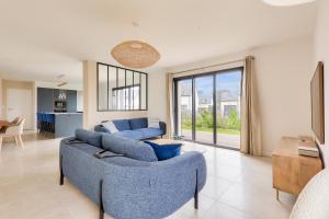 a living room with two blue couches and a kitchen at 450m de la plage, grande maison pour 10 in Saint-Philibert