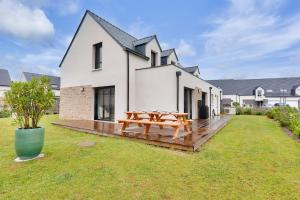 a wooden deck with a picnic table in front of a house at 450m de la plage, grande maison pour 10 in Saint-Philibert