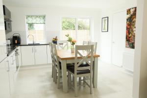 a kitchen with a wooden table and chairs at Ballintra 3 Bedroom Family Holiday Home - Near Rossnowlagh Surfing & Beach & Donegal Bay Golf in Ballintra +4 photos