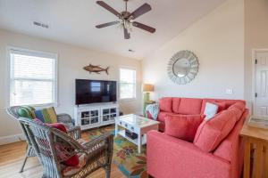a living room with a red couch and a flat screen tv at A Shore Thing in Kill Devil Hills