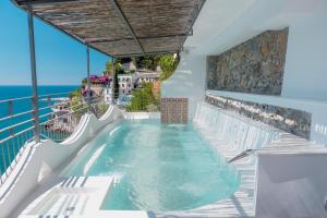 a hot tub on the balcony of a resort with the ocean at Hotel Cetus in Cetara