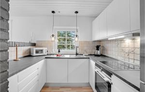 a white kitchen with a sink and a microwave at Lovely Home In Væggerløse With Wifi in Marielyst