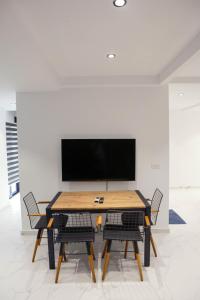 a dining room table with chairs and a flat screen tv at Sofia Apartments in Sarandë