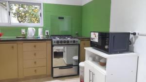 a green kitchen with a stove and a microwave at El Naranjo in Chascomús