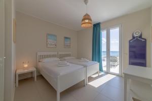 a white bedroom with a bed and a large window at Le Suites sul Mare di Esterina in Civitavecchia