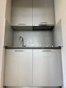 a kitchen with white cabinets and a sink at Apartment Dora 1 , on the beach in Tivat +2 photos