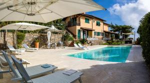 a pool with chairs and umbrellas next to a house at Il Mirto B&B in Imperia