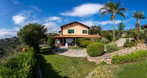 a house on a hill with palm trees and bushes at Il Mirto B&B in Imperia