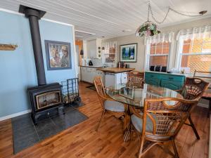 a dining room with a glass table and a fireplace at Chalet La Caille in LʼAnse-Saint-Jean