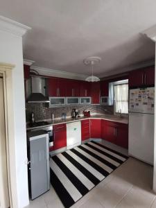 a kitchen with red cabinets and a black and white rug at Kuşadası Davutlar'da Huzur Rahat ve Konfor Bir Arada in Aydın