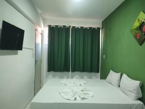 a bedroom with a white bed with a green wall at Pousada Belo Mar in Salvador
