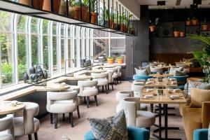 a restaurant with tables and chairs and windows at The Hotel Brussels in Brussels
