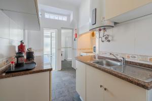 a kitchen with white cabinets and a sink at Mercy House - BY Y Concept in Setúbal +14 photos