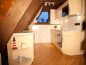 a kitchen with white cabinets and a staircase with a window at Ferienhaus in Fedderwardersiel mit Terrasse und Garten in Butjadingen