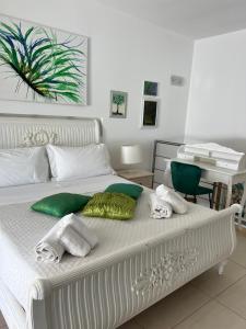 a white bed with green and white towels on it at Villa Losanna in Mondello