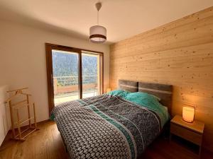een slaapkamer met een bed en een groot raam bij Thélème A202 - T4 avec vue panoramique sur la station in Châtel