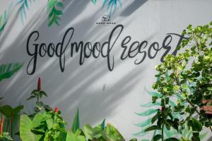 a sign on a wall with plants at Good Mood Resort in Ko Lipe