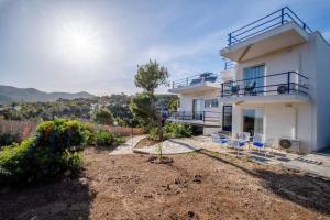 a large white house with chairs in front of it at Villa Elisa 6ppl Poseidon Temple View Sounio in Sounio