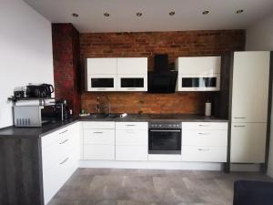 a kitchen with white cabinets and a brick wall at Haus Laila in Heidesee