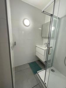 a white bathroom with a shower and a sink at Résidence Agathoise in Agde