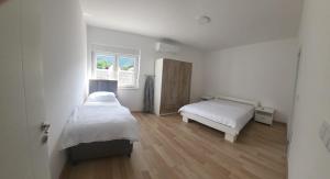 a white bedroom with two beds and a window at Meem in Konjic
