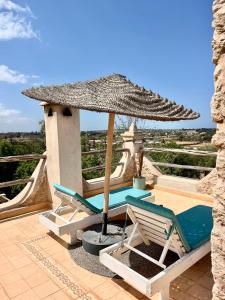 een terras met een tafel, stoelen en een parasol bij La Villa Sauvage in Essaouira