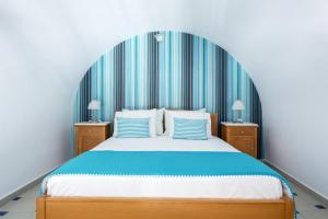 a bedroom with a large bed with a blue headboard at Santellini Hotel in Kamari