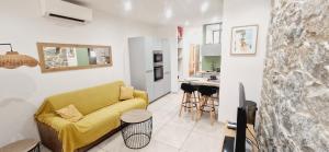 a living room with a yellow couch and a kitchen at Appartement plein de charme - Ajaccio hyper centre in Ajaccio
