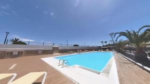ein Swimmingpool mit Stühlen und das Meer im Hintergrund in der Unterkunft DUNASOL Home, by Comfortable Luxury in Corralejo