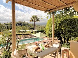 a patio with a table and a swimming pool at Toile Blanche in Saint Paul de Vence
