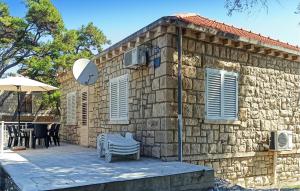 a stone house with two chairs and an umbrella at Apartment Lumbarda Iv in Lumbarda