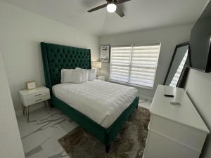 a bedroom with a bed with a green headboard and a desk at Beautifully Remodeled Home - Southen Dunes Golf Course Views in Haines City +23 photos