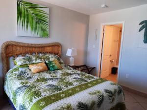 a bedroom with a bed with a green and white comforter at Daytona Beach Hawaiian Inn in Daytona Beach +83 photos