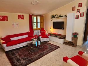 a living room with red and white furniture and a flat screen tv at Il Giardino in Calvello