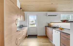a kitchen with wooden cabinets and a white door at Stunning Home In Skals With Sauna in Hjarbæk