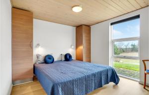 a bedroom with a blue bed and a large window at Stunning Home In Skals With Sauna in Hjarbæk