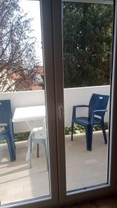a sliding glass door with two chairs and a table on a balcony at Apartmani Dream 3 in Šušanj