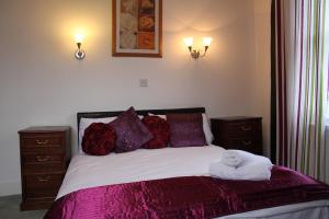 a bedroom with a bed with purple sheets and pillows at The George Hotel Stansted Airport in Bishops Stortford