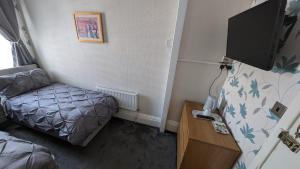 a small room with a bed and a flat screen tv at Martell's Hotel in Blackpool