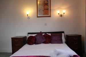 a bedroom with a bed with two night stands and two lights at The George Hotel Stansted Airport in Bishops Stortford +5 photos