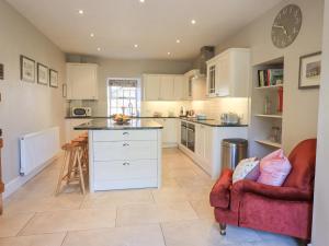 a kitchen with white cabinets and a red chair at Clock Tower in Grange Over Sands