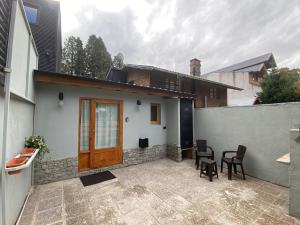 a house with a patio with chairs and a wooden door at Departamento El Origen-SMA in San Martín de los Andes